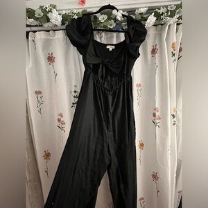 Sleek black romper with cute bow detail and puff sleeves!